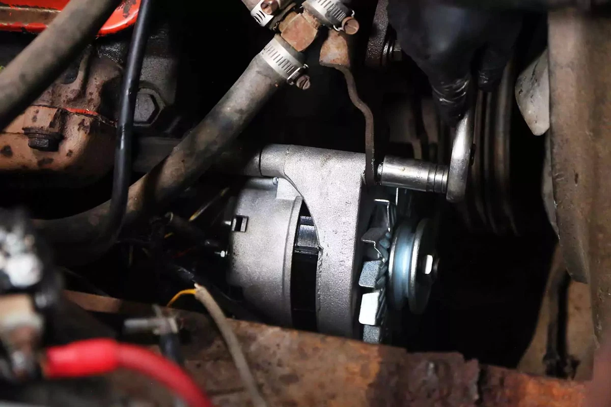 An alternator being bolted in with a socket wrench.