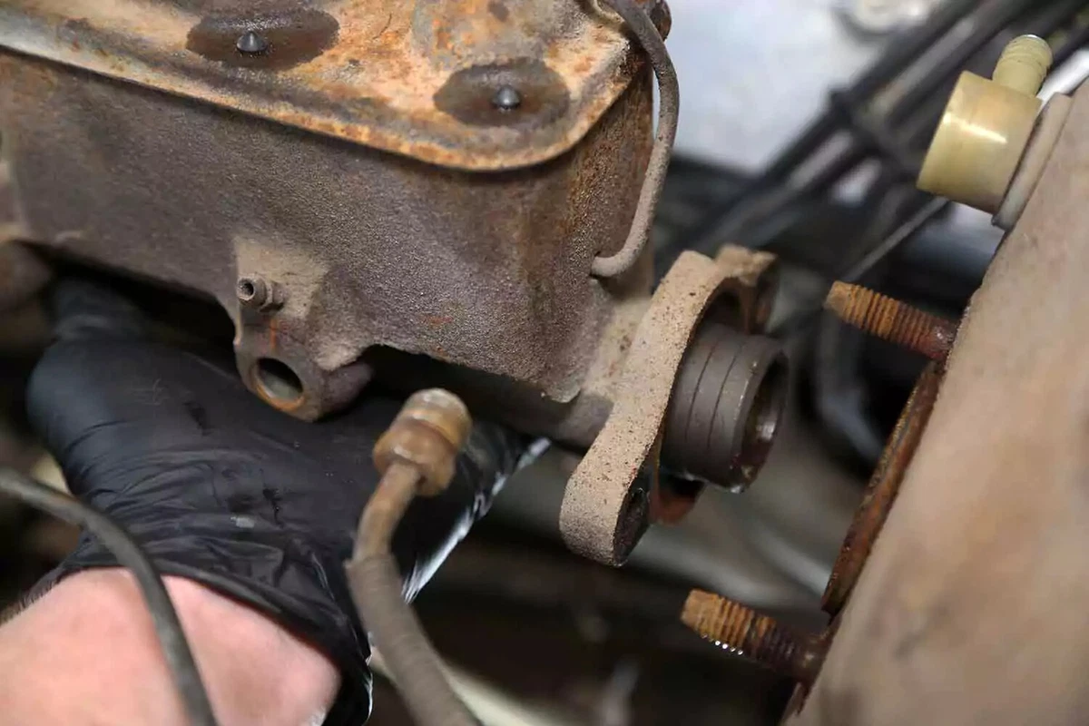 Sliding the brake master cylinder off the studs to take it out of the vehicle.