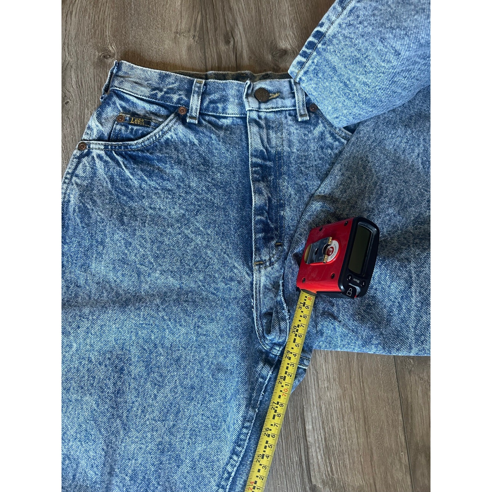 Light blue high-rise vintage Lee jeans size 8 with faded front thighs, five-pocket design, and yellow measuring tape.
