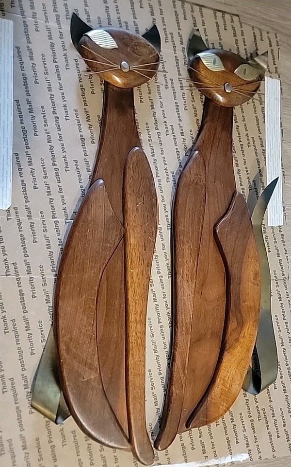 A genuine pair of 1960s brass, copper, and teak Siamese cat wall sculptures — the holy grail of MCM kitsch that interior designers and collectors actively hunt for.