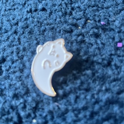cat  yang pin white with silver etchings and his toung is out  