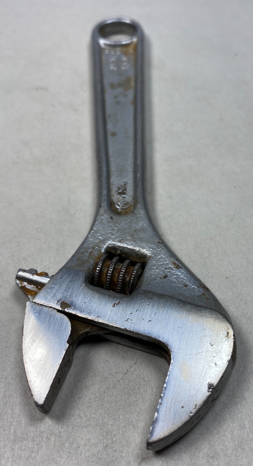 Silver 6-inch adjustable crescent wrench with worn handle, visible screw and spring tension, made in USA.