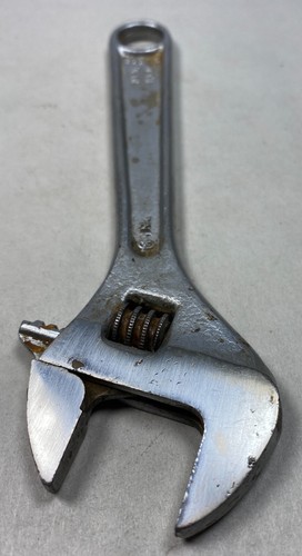 Silver 6-inch adjustable crescent wrench with worn handle, visible screw and spring tension, made in USA.