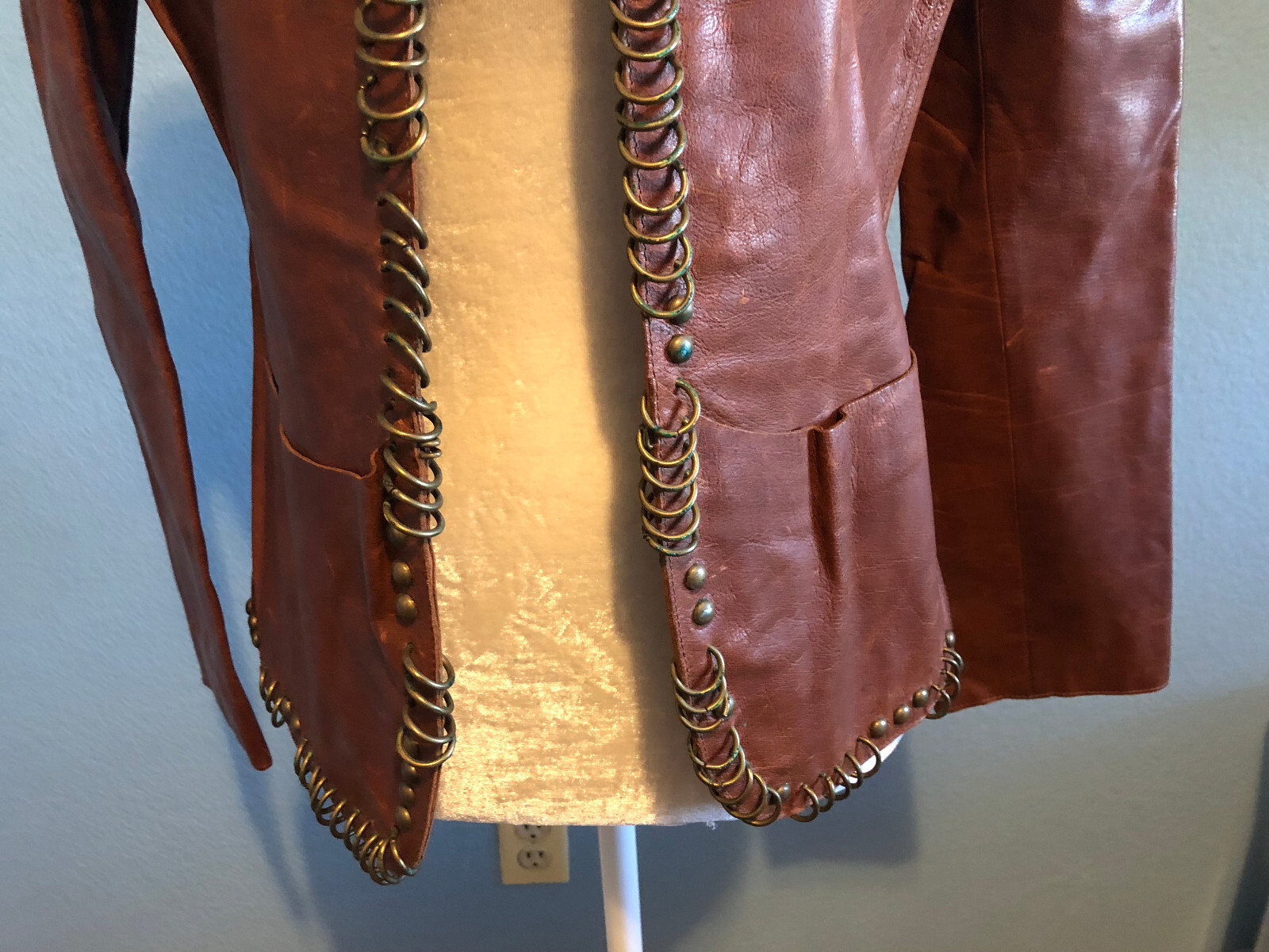 Giacca in pelle cognac design Yves Saint Laurent Tom Ford con anelli in ottone