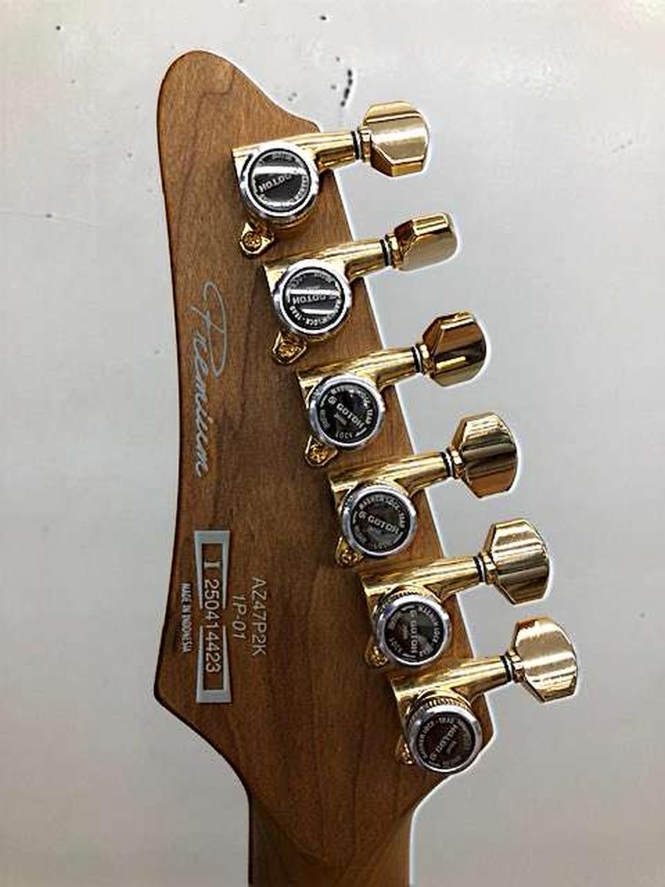 Gold Ibanez AZ47P2K Dragoneyeburst electric guitar with six tuning knobs and silver fretboard, used at the edge of the neck.