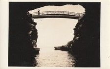 RPPC  Person on a Footbridge Fishing Over Water Outside a Cave Postcard