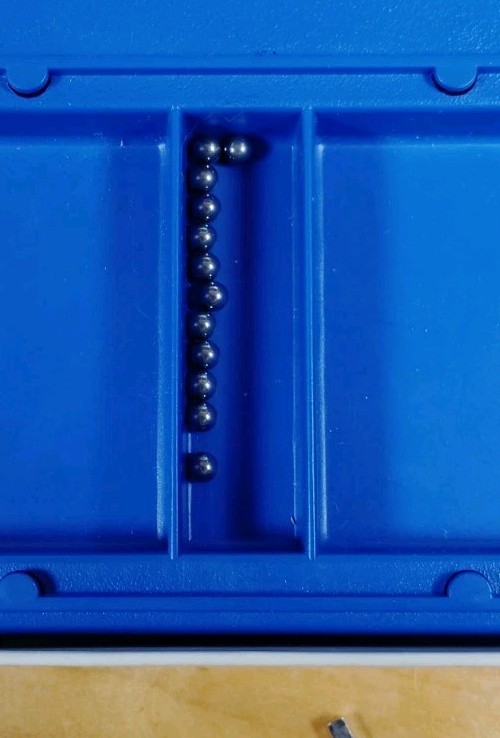 Blue Vintage Childcraft MAGNASTIKS box with two dark blue compartments and silver ball magnets on a wooden surface.