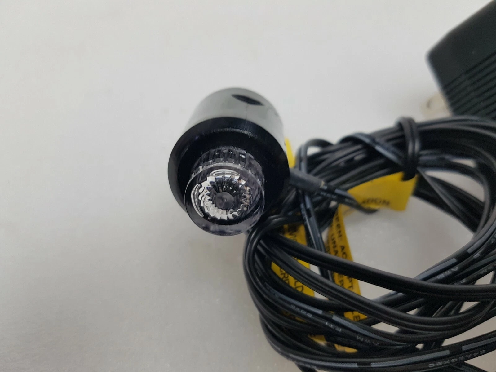 Clear lens end of the Pura-Lite indicator with the black cord coiled behind it