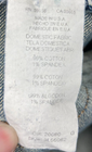 White fabric tag on blue stretch light wash Karen Kane jeans with 99% cotton and 1% spandex details.