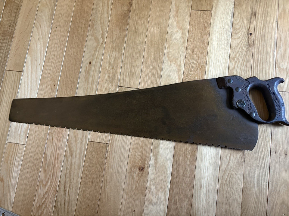 An antique 'Warranted Superior' eagle-logo hand saw with unusual decorative teeth — a wall-worthy piece of Americana that doubles as a collectible tool.