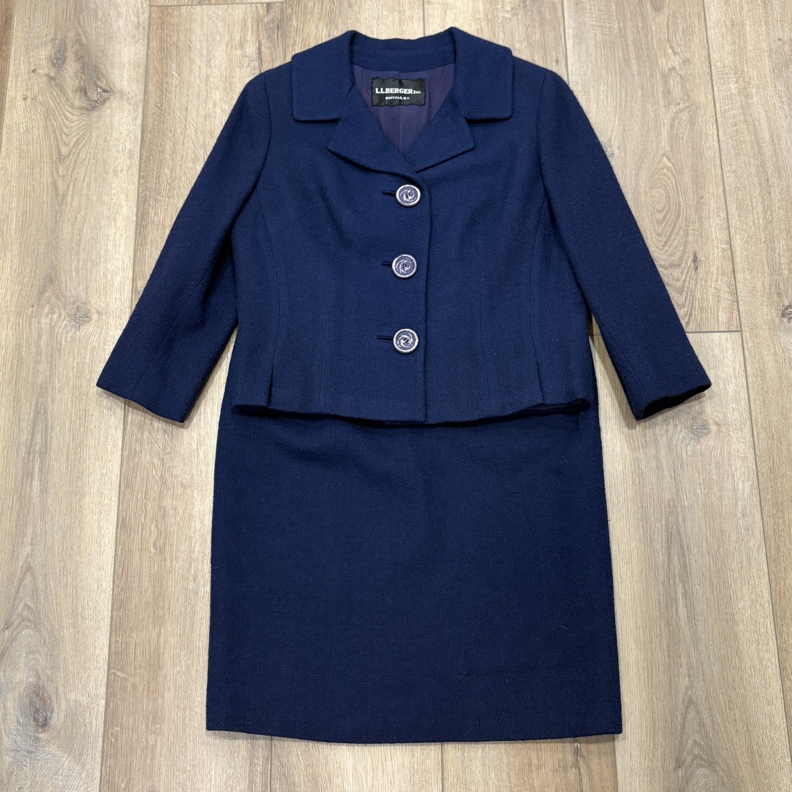 Navy wool two-piece suit with a cropped notch-collar jacket and pencil skirt, laid flat, showing the L.L.Berger label.