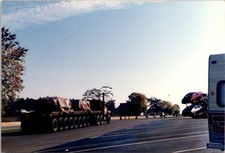Red semi w/loaded flatbed, RV & car rack trailer at rest stop Found Photo V1778