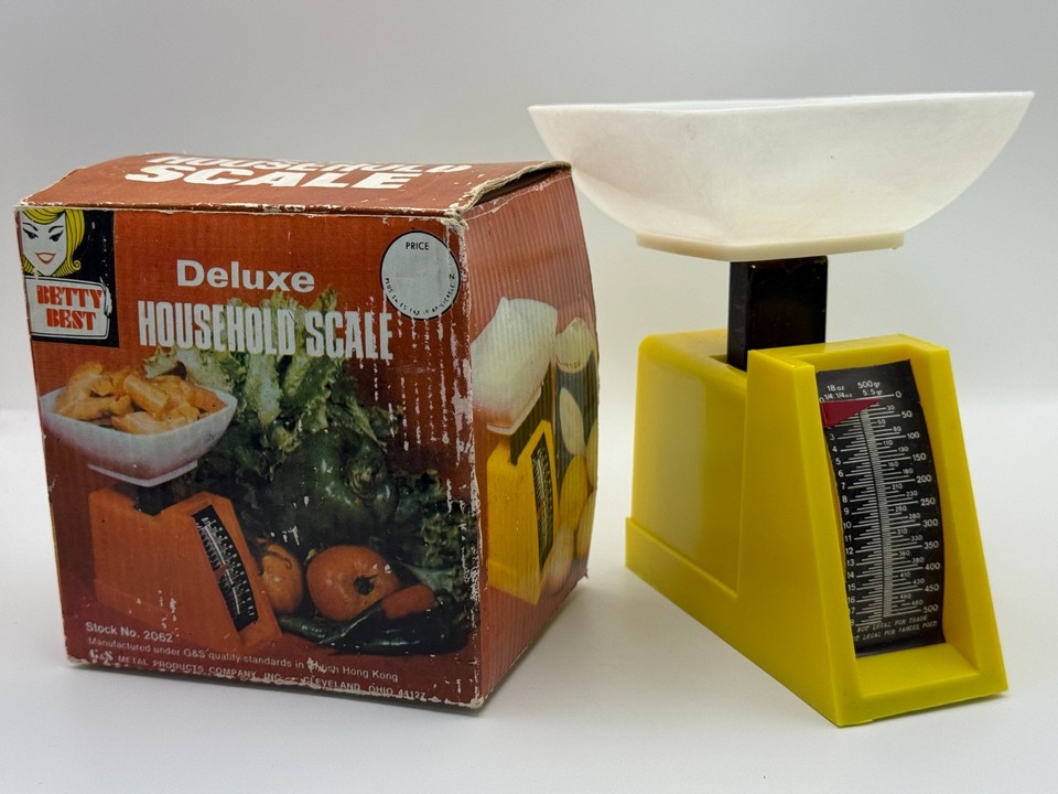 A tiny canary-yellow retro kitchen scale branded 'Betty Best' — the kind of charming analog object that makes a countertop look like a mid-century time capsule.