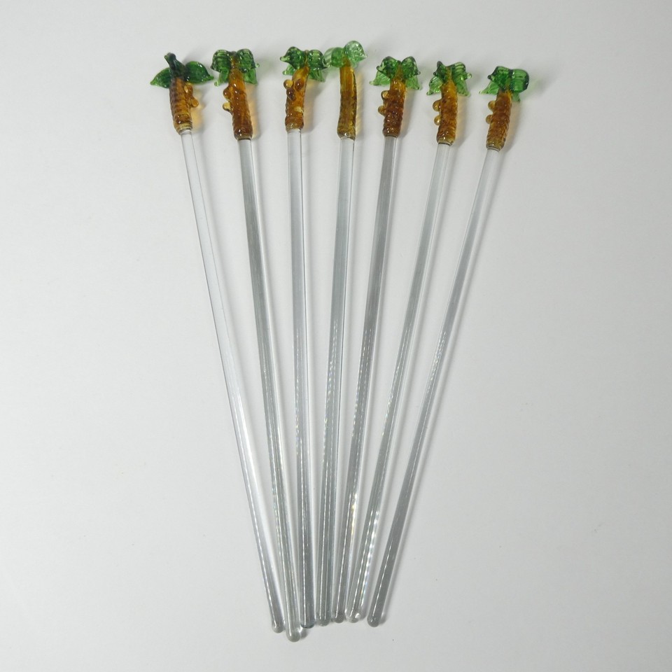 A set of 7 hand-blown glass swizzle sticks with palm tree toppers — tiny vintage craftsmanship that makes every cocktail feel like a tiki vacation.