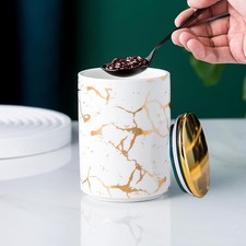 Elegant ceramic food storage jar with golden marble design, black and white,