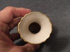 White ceramic vase with scalloped rim and gold band, 4.25 inches tall, held in a hand against a gray background.