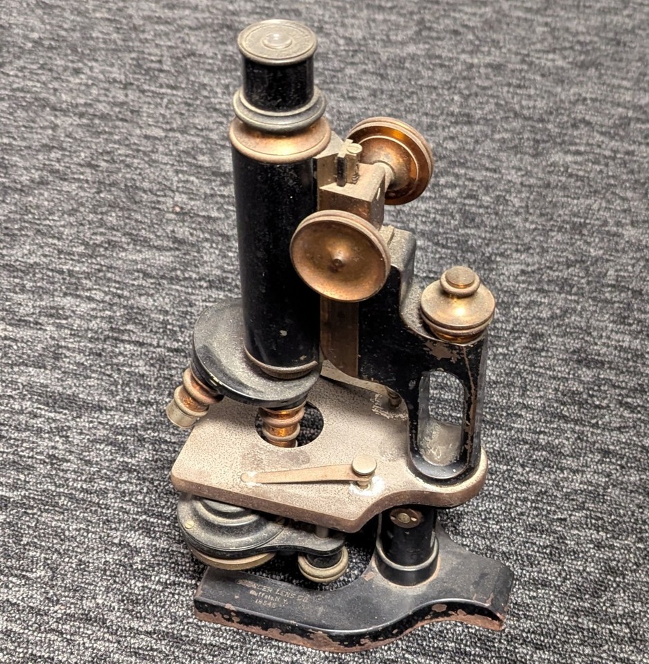 A gorgeous all-brass 'jug handle' microscope from Spencer Lens Co. — a genuine Victorian scientific instrument that doubles as sculptural shelf art.