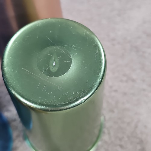 Close-up of worn green aluminum tumbler with faint scratches and circular hole near the end.