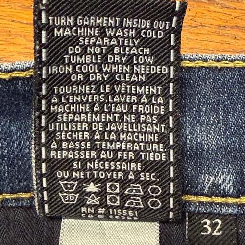 Yellow printed inner label on 7 For All Mankind denim shorts, size 32, with black text and white laundry symbols.