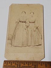 An 1870s CDV of twin girls in matching dresses, one reportedly blind, posed identically — quietly haunting and historically poignant.