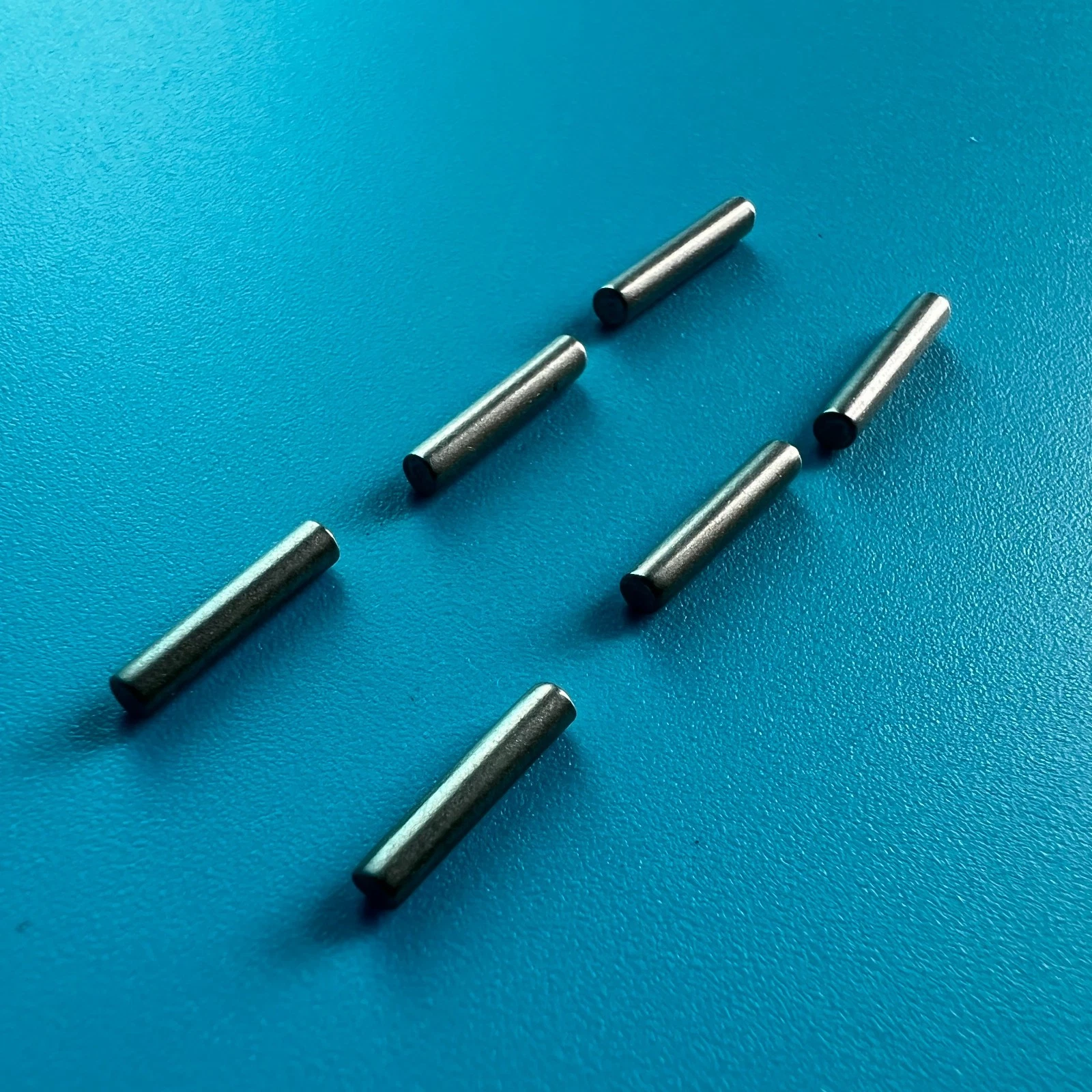 Six silver metal pin A21888 for Noritsu QSS29/30/31/32/33/37 minilabs on a teal surface.