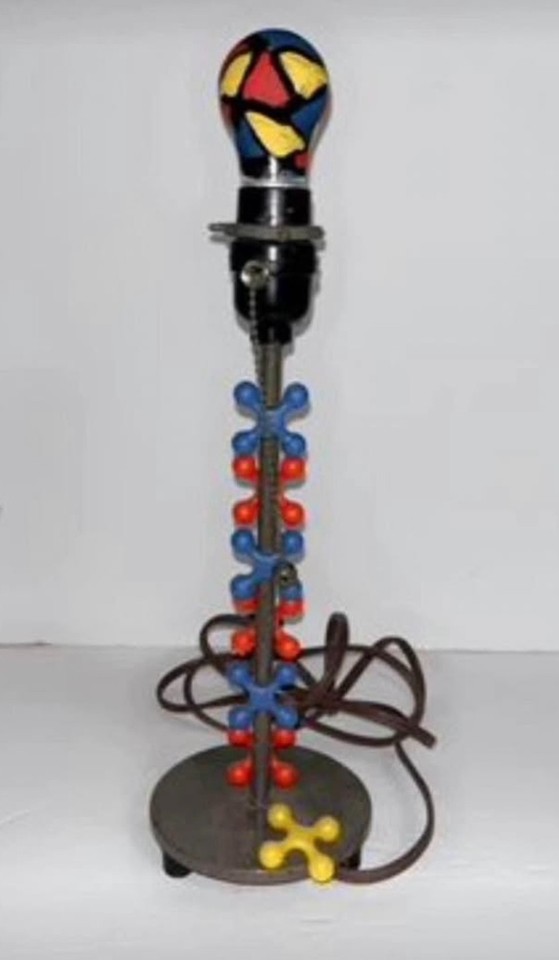 A one-of-a-kind handmade stained glass lamp built around giant metal jacks — genuinely bizarre, sculptural, and conversation-stopping.