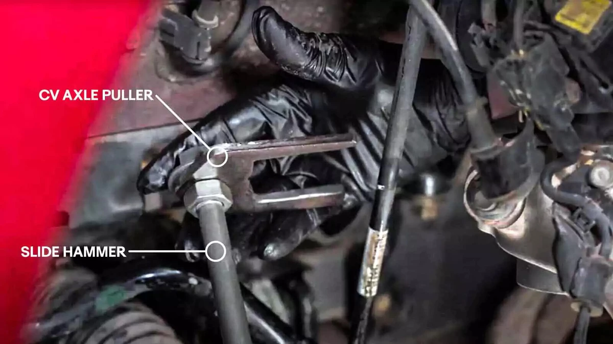 An annotated photograph shows a mechanic using a slide hammer and CV axle puller to remove a CV axle.