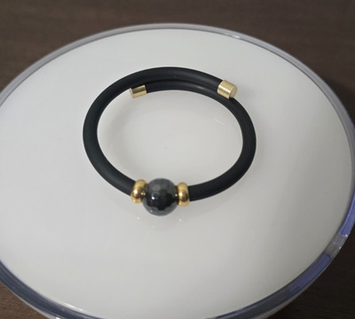 Open golf bracelet in black rubber with faceted onyx and 18K gold-plated silver.