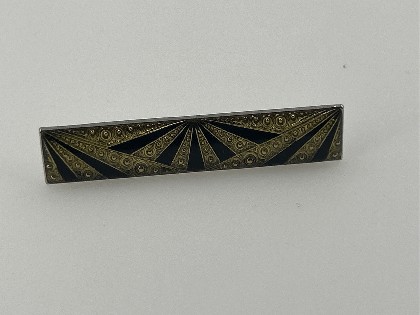 Black and gold enameled rectangular bar brooch with a radiating sunburst pattern