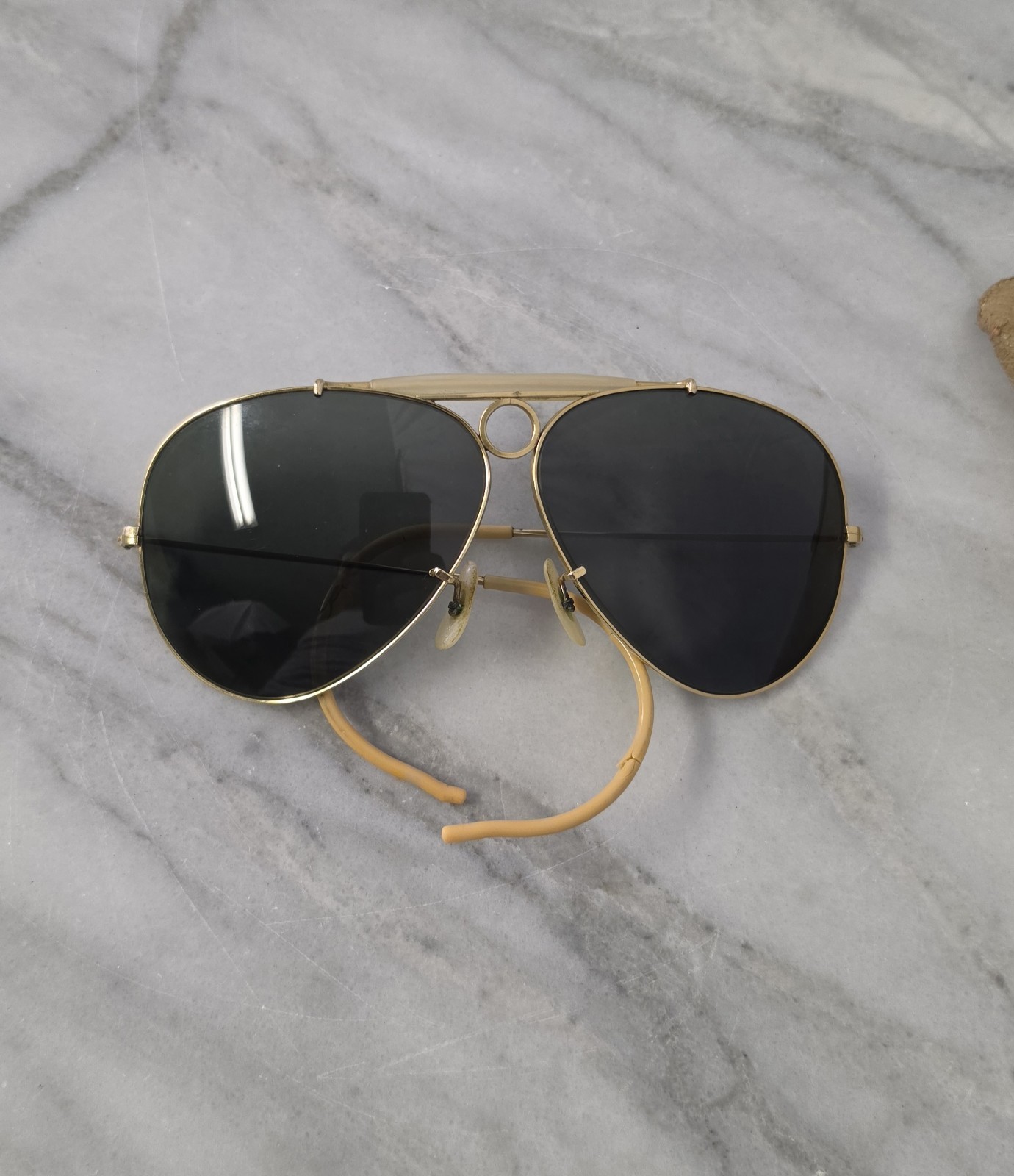 Gold-toned aviator sunglasses with small vent openings on the temples, photographed flat.