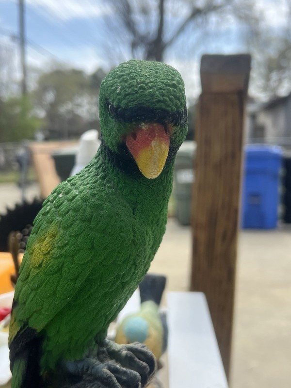 This is a vintage ceramic sand art parrot figurine perched on a branch