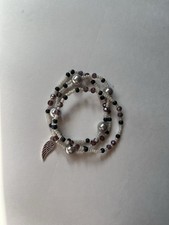 3 Elastic Bracelets Held Together By A Ring Featuring A Wing Charm