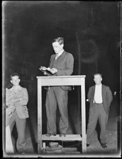 Lance Sharkey giving a speech with two other men in the background - Old Photo