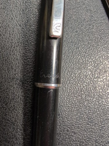 Black Eversharp mechanical pencil with silvertone trim, blue “Eversharp” text, and twist-out pen refills on a textured surface.