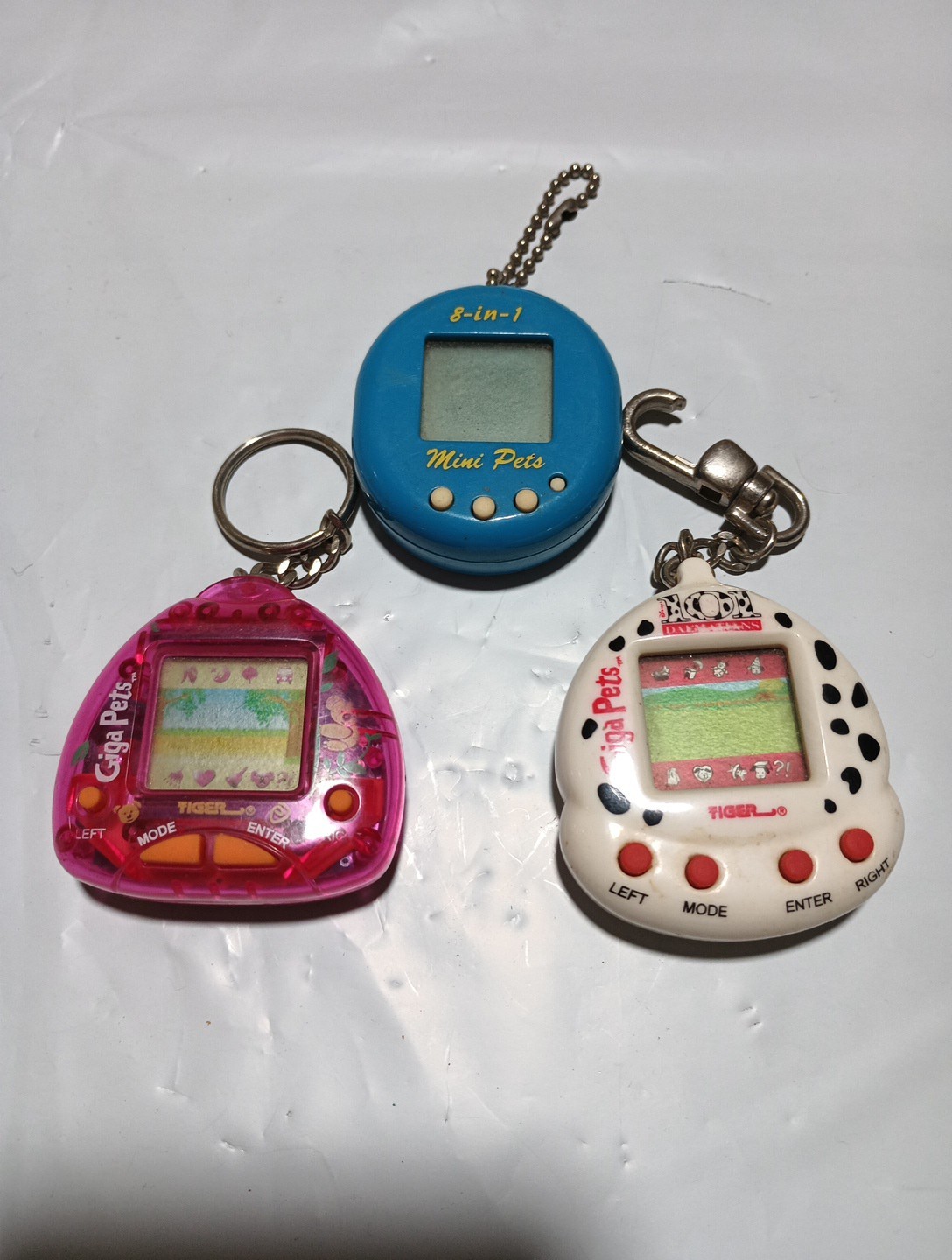 two giga pets keychain games and one 8-in- 1 mini pets 