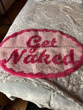 Small oval shaped hot pink bath mat with the cute phrase Get Naked imprinted on