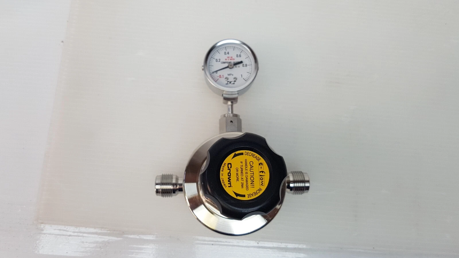 Top view of the Crown e-flow regulator with yellow knob cap, compound gauge and IN/OUT ports