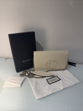 Die elfenbeinfarbene Gucci Soho Geldbörse an...