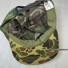 Green and brown camouflage hunting mosquito net facemask with black strap and visible “Vtg Camo” logo on front.