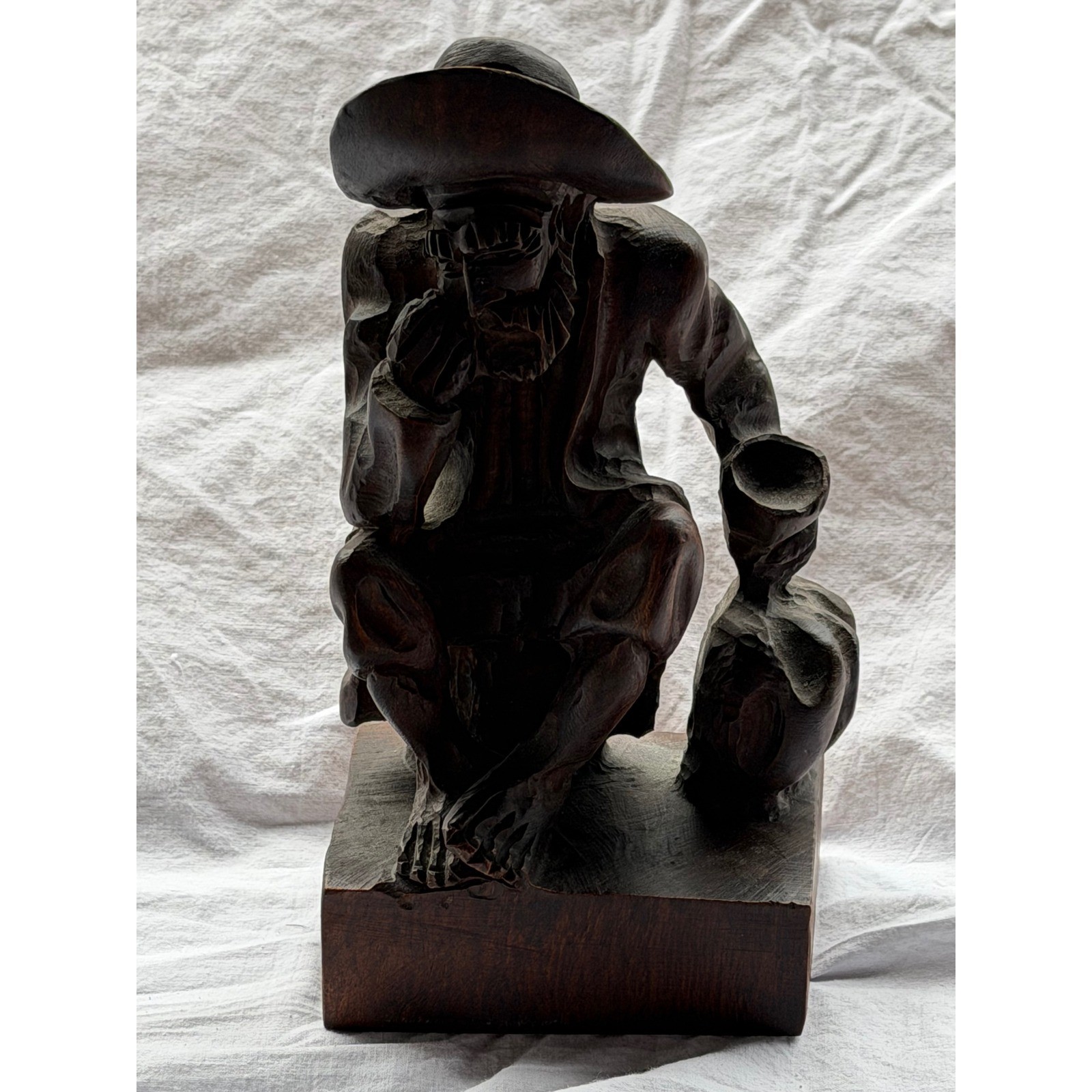 Carved wood folk art figurine of a seated man in a hat