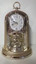 Rhythm Quartz mantel clock with a rotating pendulum and musical cherub figures.