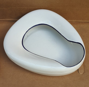 vintage white porcelain enamel bed pan, featuring a blue trim.