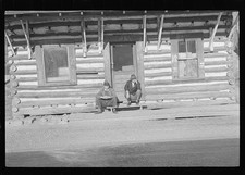 Foto: Cabaña de troncos de la década de 1930 dos hombres en el porche fotografía de cabaña rústica