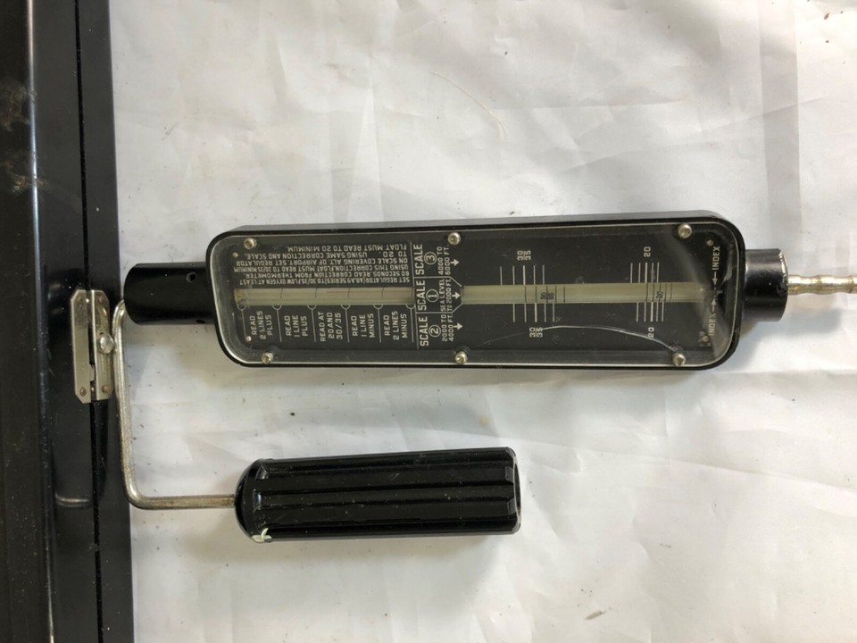 A WWII-era USAAF ground flow check meter — a piece of aviation history with striking industrial design that reads as serious art object on a desk.
