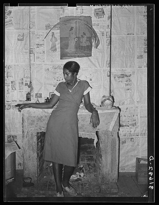 Negro girl in front of fireplace in home along levee near Norco, Louisiana