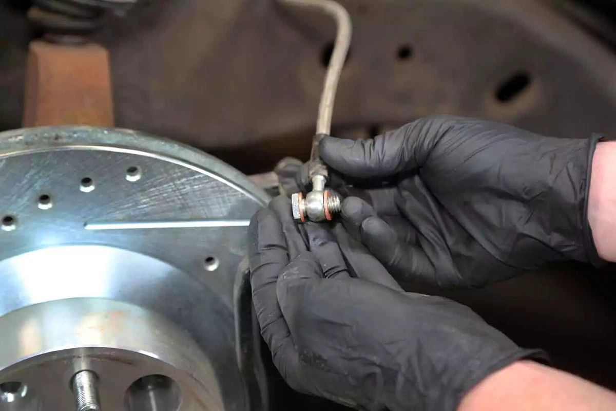 A mechanic installs new crush washers on the brake line.