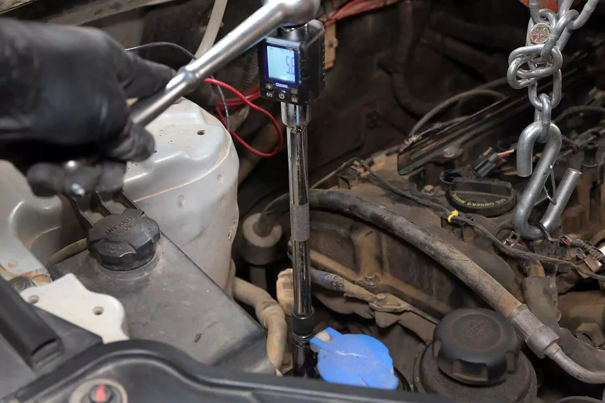Mechanic using a torque wrench to tighten the motor mount bolt.