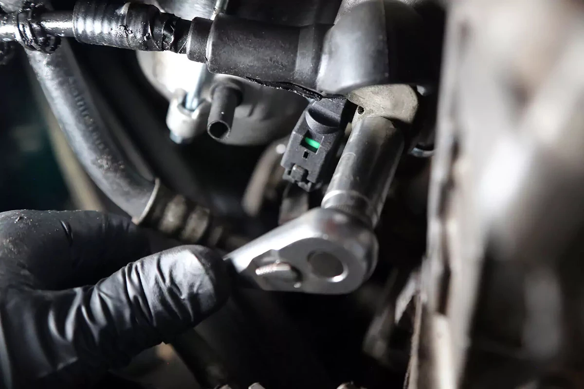 Tightening the bolt on the starter’s battery lug with a socket wrench.