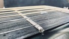 Close-up of black Martin D-76 guitar with silver hardware and three straight guitar strings on a dark wood fretboard.