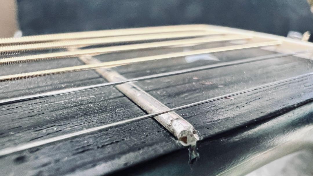 Close-up of black Martin D-76 guitar with silver hardware and three straight guitar strings on a dark wood fretboard.